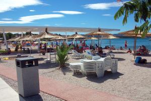 plaża z leżakami i parasolami oraz ludzie na plaży w obiekcie Apartments by the sea Sibenik - 18501 w Szybeniku