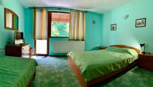 a blue bedroom with two beds and a window at Sun House in Tryavna