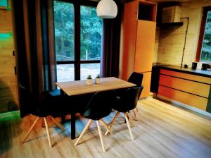 una mesa de madera y sillas en una habitación con ventana en Ranczo w lesie - domki z jacuzzi en Ożarów
