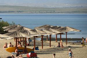 eine Gruppe von Menschen mit Sonnenschirmen an einem Strand in der Unterkunft Apartments by the sea Nin, Zadar - 19103 in Nin + 7 Fotos