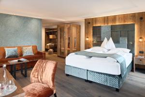 a bedroom with a large bed and a couch at Hotel Comploj Adults only in Selva di Val Gardena