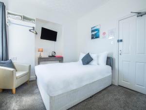 a white bedroom with a bed and a chair at OYO Pier Hotel in Clacton-on-Sea