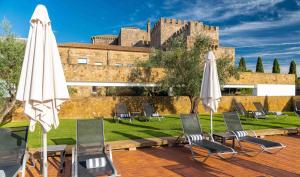 two white umbrellas and chairs with a castle in the background at Pousada Mosteiro do Crato in Crato