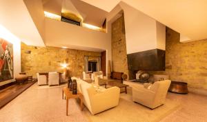 a living room with white furniture and a stone wall at Pousada Mosteiro do Crato in Crato