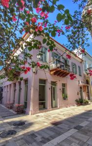 a pink building with a balcony and flowers at Andromeda Suites in Nafplio