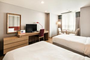 a hotel room with two beds and a desk with a television at Ramada Hotel and Suites Seoul Namdaemun in Seoul