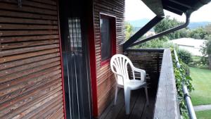 uma cadeira branca sentada no alpendre de uma casa em Ferienhaus am Eichert em Furth im Wald