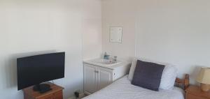 a bathroom with a tv and a sink and a chair at Private Rooms just 19 minutes from Central London in Northfleet