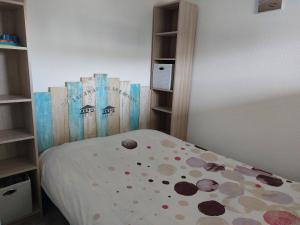 a small bedroom with a bed with polka dots at Appartement T 2 AVEC PISCINE in Lacanau
