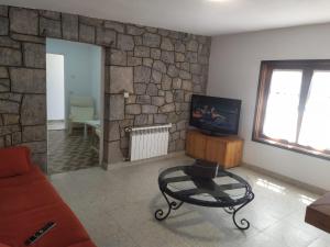 sala de estar con sofá, TV y pared de piedra en Villa Noriega (La Franca) en La Franca