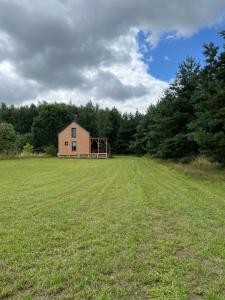 um grande campo com uma casa no meio dele em Baciki 61- domek przy lesie em Baciki Dalsze