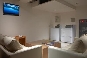 a living room with two white chairs and a flat screen tv at Beauty Hotels - Roumei Boutique in Taipei