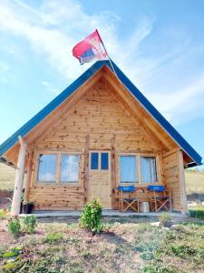 una cabaña de madera con una bandera encima en Markove kolibe 4, Uvac, en Sjenica