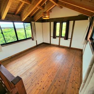 ein leeres Zimmer mit Holzböden und großen Fenstern in der Unterkunft koco in Nishinoomote