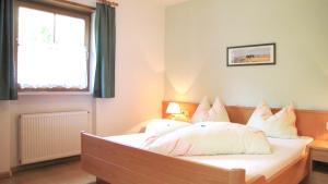a bedroom with a bed with white pillows and a window at Ferienwohnungen Günzelgut in Lana +38 photos