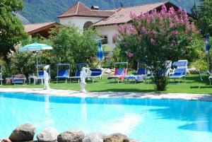 a swimming pool with chairs and umbrellas in a resort at Ferienwohnungen Günzelgut in Lana