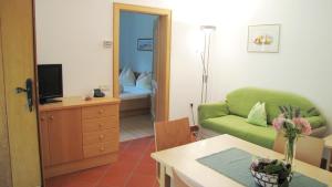 a living room with a green couch and a television at Ferienwohnungen Günzelgut in Lana