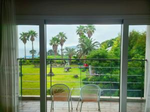 a room with a window with chairs and palm trees at Dombe Resort in Seogwipo
