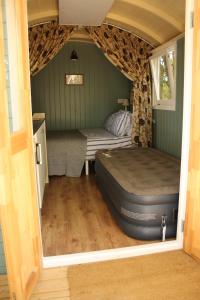 a bedroom with a bed and a couch in a room at The Kestrel Shepherd Hut, Whitehouse Farm in Stowmarket