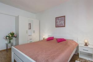 a white bedroom with a large bed with pink pillows at Apartments with parking space Novigrad - 2536 in Novigrad Istria