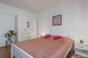 a white bedroom with a large bed with pink pillows at Apartments with a parking space Novigrad - 2536 in Novigrad Istria