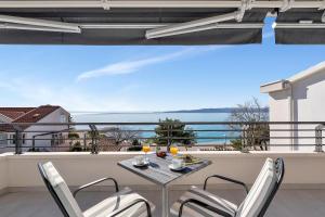 a balcony with a table and chairs and a view of the ocean at Apartments and rooms by the sea Baska Voda, Makarska - 2578 in Baška Voda