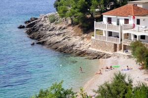 grupa ludzi na plaży obok domu w obiekcie Seaside secluded apartments Cove Tvrdni Dolac, Hvar - 4008 w mieście Gdinj