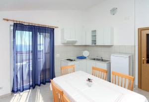 uma cozinha com uma mesa e cadeiras e um frigorífico em Apartments with WiFi Seget Vranjica, Trogir - 4870 em Trogir