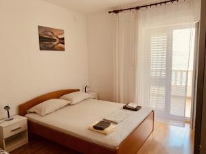 a white bedroom with a bed and a window at Apartments with a parking space Sobra, Mljet - 4926 in Babino Polje