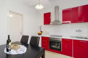 una cocina con armarios rojos y una mesa con una botella de vino en Apartments by the sea Sobra, Mljet - 4889 en Babino Polje