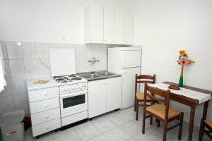 una cocina con electrodomésticos blancos y una mesa con sillas. en Apartments with a parking space Lokva Rogoznica, Omis - 4819 en Lokva Rogoznica