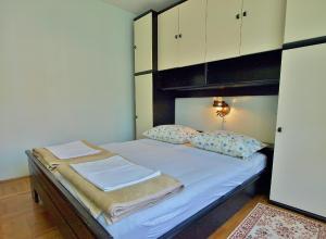 Schlafzimmer mit einem Bett mit weißer Bettwäsche und Kissen in der Unterkunft Apartments with a parking space Kampor, Rab - 5000 in Rab