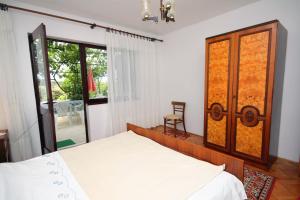 a bedroom with a bed and a chair and a window at Apartments by the sea Supetarska Draga - Gonar, Rab - 4989 in Supetarska Draga