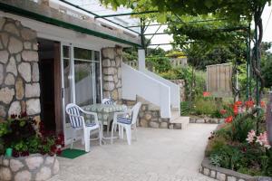 a patio with a table and chairs on a house at Apartments by the sea Supetarska Draga - Gonar, Rab - 4989 in Supetarska Draga