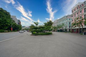 an empty street in a city with cars driving down it at De Charm Hạ Long Hotel in Ha Long