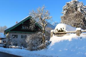 a house covered in snow next to a fence at Ferienwohnung Wagnerhaus in Bad Reichenhall