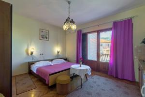 1 dormitorio con 1 cama con cortinas moradas y mesa en Apartments and rooms with parking space Jelsa, Hvar - 4028, en Jelsa