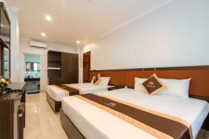 a hotel room with two beds and a bathroom at De Charm Hạ Long Hotel in Ha Long