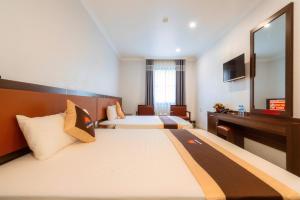 a hotel room with two beds and a desk at De Charm Hạ Long Hotel in Ha Long