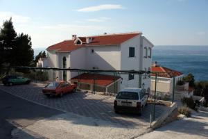 a house with two cars parked in a parking lot at Apartments by the sea Balica Rat, Omis - 4868 in Čelina