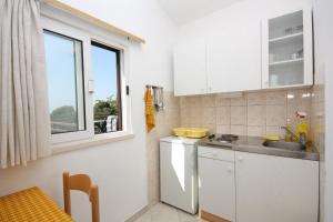 a kitchen with white cabinets and a sink and a window at Apartments with parking space Maslinica, Solta - 5184 in Grohote +29 photos