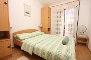 a small bedroom with a bed and a window at Apartments with parking space Maslinica, Solta - 5184 in Grohote