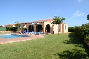 a house with a swimming pool and two lawn chairs at Villas Las Golondrinas in Cala'n Bosch