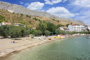een strand met mensen en boten in het water bij Apartments by the sea Duce, Omis - 5275 in Dugi Rat