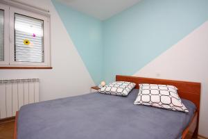 Un dormitorio con una cama con dos almohadas y una ventana. en Apartments and rooms by the sea Barbat, Rab - 5068, en Rab