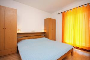 a bedroom with a bed and a yellow curtain at Apartments and rooms by the sea Palit, Rab - 5044 in Rab
