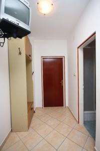 a hallway with a door and a television on a wall at Apartments and rooms by the sea Palit, Rab - 5044 in Rab