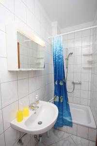 a bathroom with a sink and a blue shower curtain at Apartments and rooms by the sea Palit, Rab - 5044 in Rab