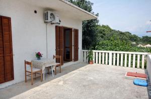 Cette petite maison blanche dispose d'un balcon avec une table et des chaises. dans l'établissement Apartments and rooms by the sea Cove Saplunara, Mljet - 4907, à Saplunara