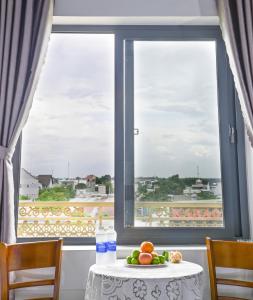 a table with a plate of fruit in front of a window at Ruby Hotel - Tân Uyên - Bình Dương in Hoi Nghia